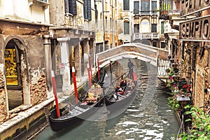 Venice, Italy Ã¢â¬â December 21, 2015: Venetian gondolier punting gondola with tourists through canal. Venice. Italy.